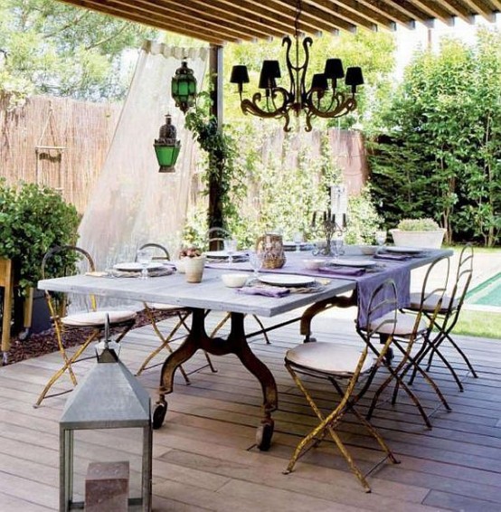 a vintage meets rustic patio with exquisite furniture, some lanterns and a chandelier plus curtains