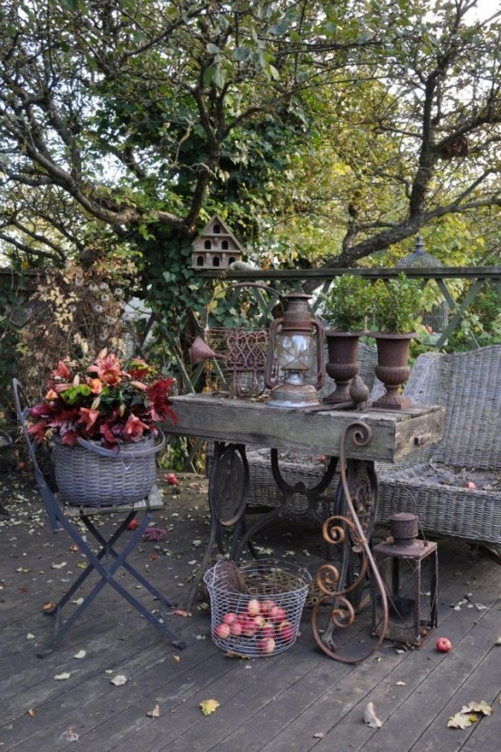 a vintage meets rustic patio with wicker furniture, a vintage stone and metal table, potted leaves