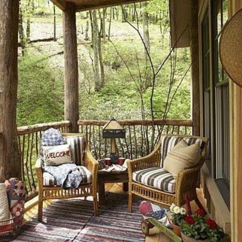 a small rustic patio with wicker furniture, potted blooms and colorul textiles