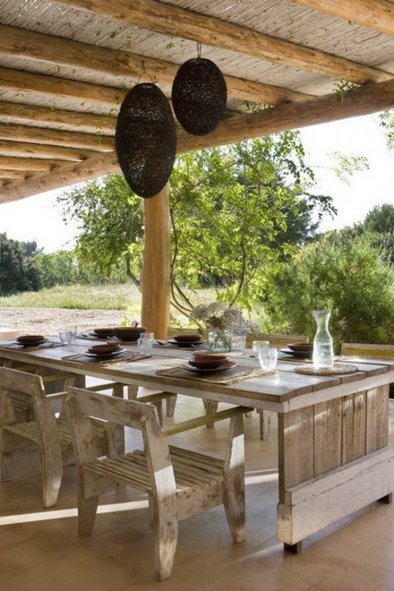 a cozy rustic patio with a shabby chic whitewashed wooden dining set and wicker lamps