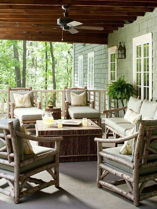 a cozy rustic patio with wooden furniture, a stick side table and coffee table plus potted greenery