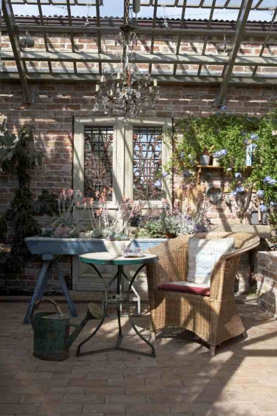 a rustic meets vintage patio with vintage and wicker furniture, with a crystal chandelier and potted blooms