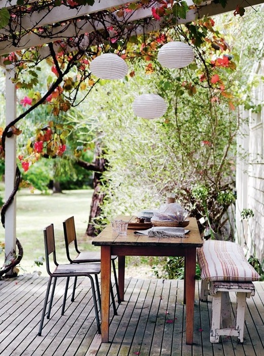 a rustic vintage patio with wooden and metal furniture, lanterns and lots of greenery