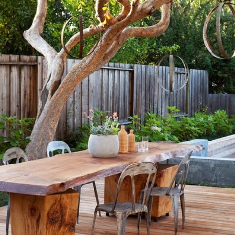a rustic meets conemporary patio with a living edge table, metal chairs and metal sphere lamps