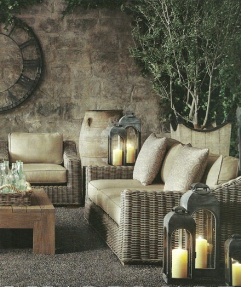 a Mediterranean rustic patio with wicker furniture, potted greenery, candle lanterns and a vintage clock