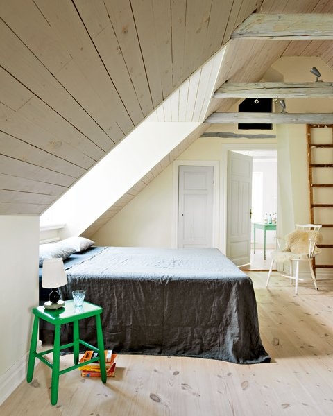a laconic attic Nordic bedroom with a skylight, wooden covered walls and floor, some vintage furniture
