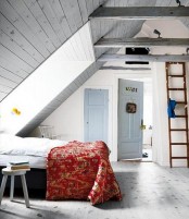 an attic Nordic bedroom with wooden planks on the ceiling, a skylight, vintage furniture and a ladder