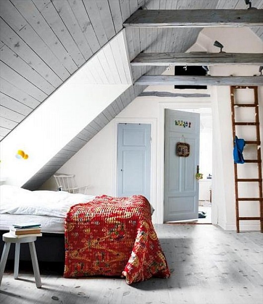 an attic Nordic bedroom with wooden planks on the ceiling, a skylight, vintage furniture and a ladder