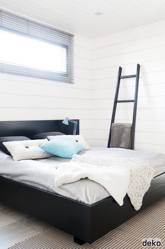 a peaceful bedroom done with white shiplap, a black bed for a contrast, a black ladder and touches of light blue