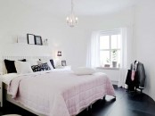 a welcoming bedroom in black and white plus slight pink touches, pillows, a crystal chandelier