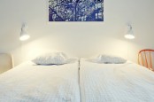 a Nordic bedroom with chairs and beds, wall lamps and a bright artwork