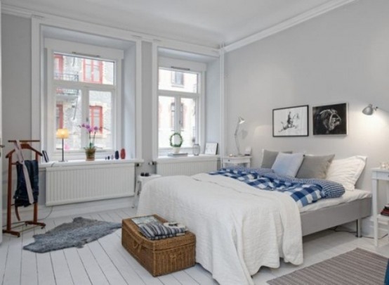 an airy Nordic bedroom with a grey bed, a basket for storage and some retro furniture