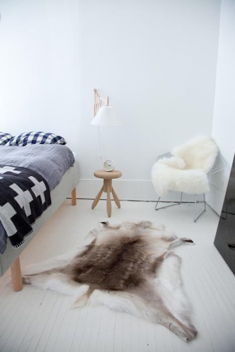 a Nordic bedroom with a wooden bed, graphic bedding and lots of faux fur for coziness