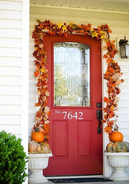 A super bright fall leaf garland over the door and some pumpkins in urns make the front door stylish and fall like