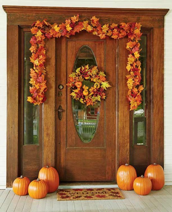 orange pumpkins and a lush fall leaf garland with pumpkins and berries over the door for a stylish Thanksgiving front door
