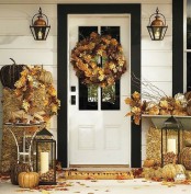 gold hay, leaves, pumpkins, candle lanterns with acorns, vine pumpkins make the front door sunny and cozy