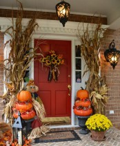 corn husk arrangements, natural pumpkin stacks, bold fall blooms and candle lanterns and a faux bloom arrangement on the door for a rustic feel