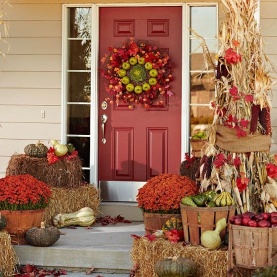 baskets with bold fall blooms, fruits and veggies, corn and corn husks, a wreath of fall leaves and green apples for Thanksgiving