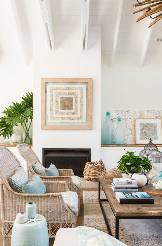 an ocean or coastal living room with a built-in fireplace, a wooden coffee table, wicker chairs, a basket for storage and some light blue and aqua touches for decor