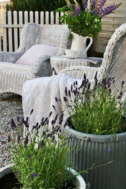 A lovely Provence inspired with white wicker chairs, a side table, potted lavender, a jug with blooms and greenery