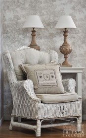 a lovely neutral reading spot with a white wicker chair with a pillow, a sideboard with matching table lamps is cool