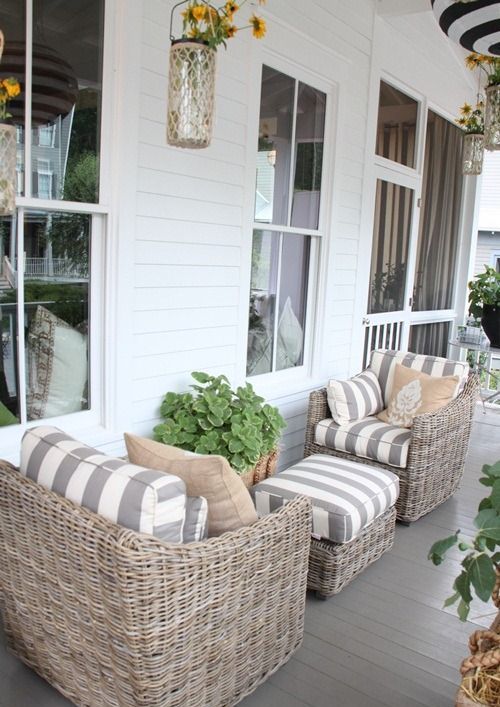 beautiful neutral wicker chairs with striped upholstery, a matching pouf and a basket with greenery for a lovely coastal outdoor space