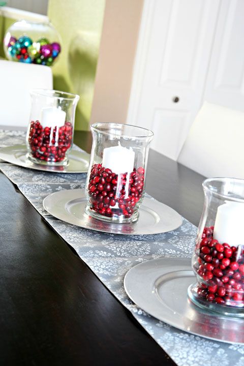a row of silver trays with glasses filled with cranberries and candles is a nice decor idea for Christmas or a centerpiece
