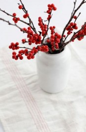 a white bottle-shaped vase with holly berries is a lovely decor idea for the holidays, and it’s very easy to compose