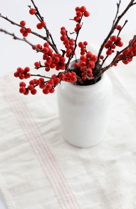 A white bottle shaped vase with holly berries is a lovely decor idea for the holidays, and it's very easy to compose