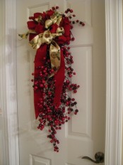 a Christmas swag with lots of cranberries and holly berries plus gold and red ribbons and ribbon bows is a cool holiday decoration to rock