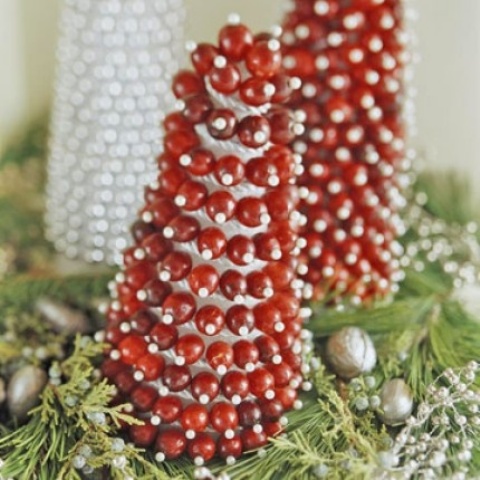 a cone shaped cranberry Christmas tree placed on greenery is a gorgeous decor idea for any space