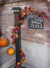 a chic chalkboard sign with fake leaves and bright pumpkins next to it is a very cool and bold idea