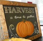 a chalkboard sign with white letters and a painted pumpkin in a simple stained wooden frame is a cool fall decoration