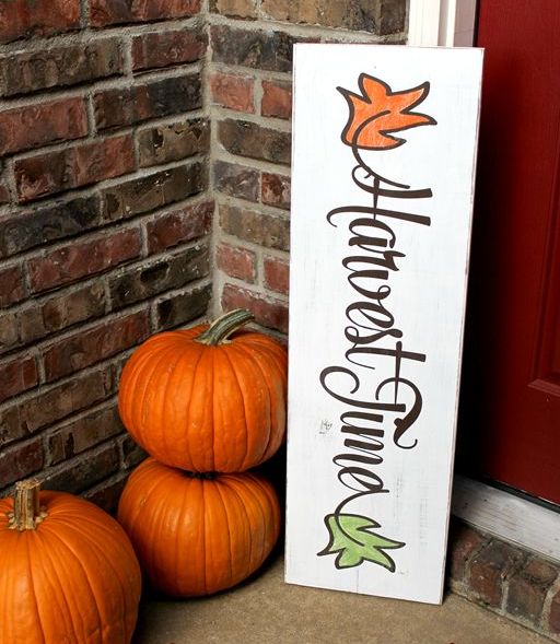 a white fall sign with colorful leaves and bright orange pumpkins for decorating your porch