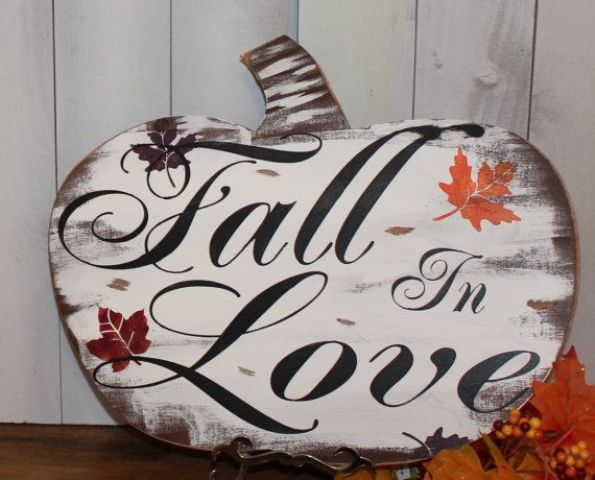 A pumpkin shaped fall sign with black letters and fall leaves is a cute piece with an unusual shape