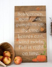 a beautiful wood plank sign with pumpkins and fall leaves plus a wooden basket with apples next to it