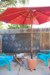 a chalkboard, colorful chalk, bright chairs, a red umbrella is a cool kids’ creativity nook – and not only for kids