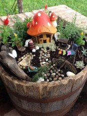 a little fairy garden of a wooden bucket, some plants and blooms and a mushroom house – add some tiny dolls and let your kids play with them