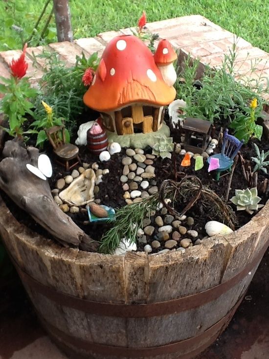 a little fairy garden of a wooden bucket, some plants and blooms and a mushroom house - add some tiny dolls and let your kids play with them