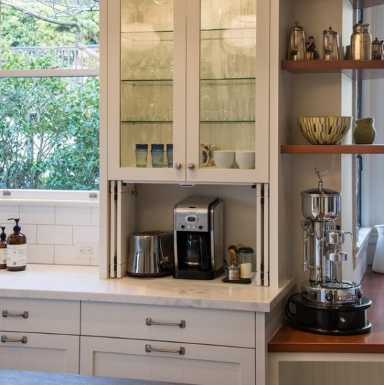 a glass cabinet with a lower part with a folding door and a coffee machine and toaster hidden here to keep the kitchen decluttered