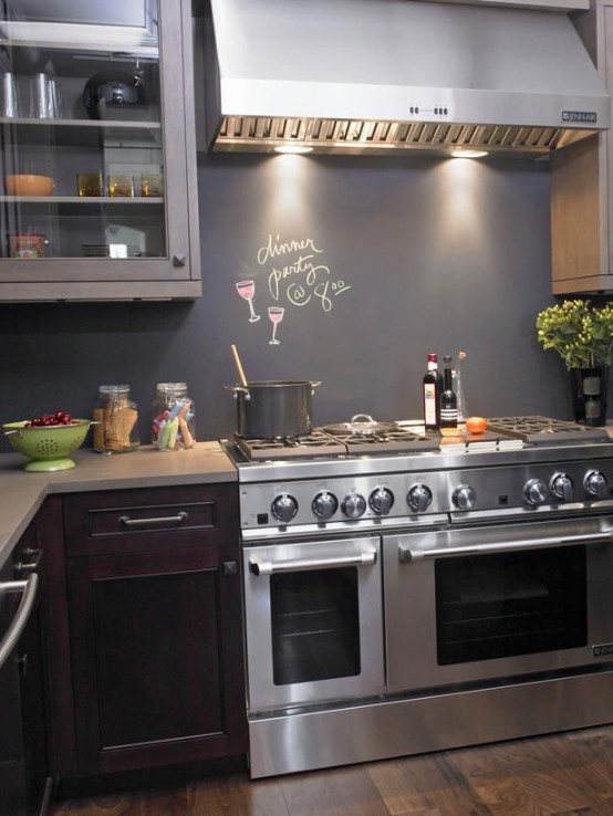 a dark kitchen with purple lower cabinets and grey upper ones, a chalkboard backsplash and lights over the cooker is very chic