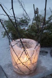 a simple ice luminarie with twigs in it is a cool rustic decor idea for a garden or a porch and it’s pretty easy to make