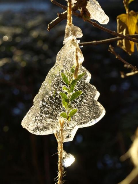 An ice Christmas tree shaped ornament with some leaves inside and some threads to hang it is a cool rustic decor idea for a winter garden