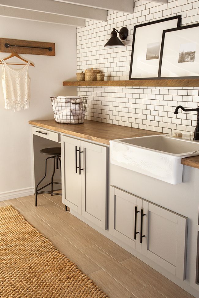 A modern farmhouse with dove grey shaker style cabinets, white subway tiles and an open shelf and racks is a lovely space