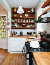 a small modern kitchen done in white and rich stained wood, with lots of open shelves and white tiles