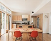 a small contemporary kitchen done with light stained wooden cabinets, a table and rust chairs