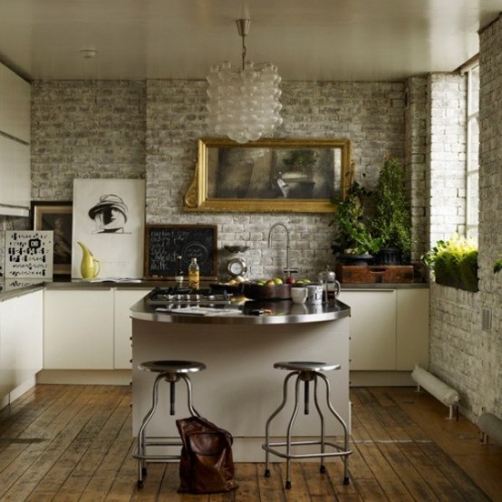 a small glam kitchen with brick walls, white cabinets and metal countertops, a frosted glass chandelier