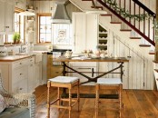 a small farmhouse kitchen with white cabinets, light stained countertops, a vintage table and carved stools, pendant lamps