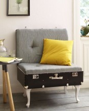 a lovely chair made of a vintage suitcase placed on legs, with cushions for comfortable sitting and a bright pillow – such a cool DIY