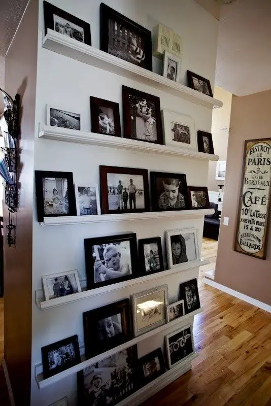 an oversized gallery wall with white ledges and black and white photos in mismatching black and white frames is a timeless idea